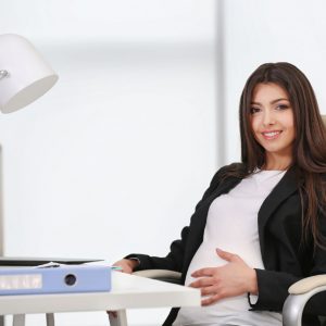 Pregnant woman sitting at her workplace in the office